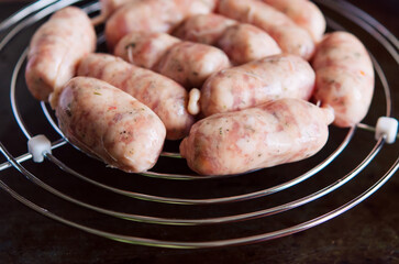 Raw sausages with spices on a round metal grill on a dark metal background with copy space for your text. Top view