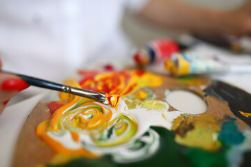 Obraz premium Close-up of paintbrush with mixed yellow and red paints