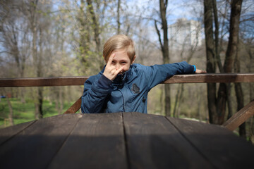 Fototapeta premium The boy sits at a wooden table in a cafe and makes various gestures with his hands