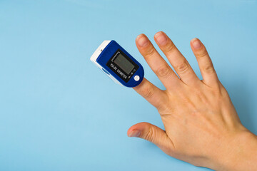 A pulse oximeter is on the woman's hand. A pulse oximeter used to measure heart rate and oxygen levels.. Covid-19