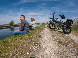 Young couple making brake at the riverside while bike trip - 430025534