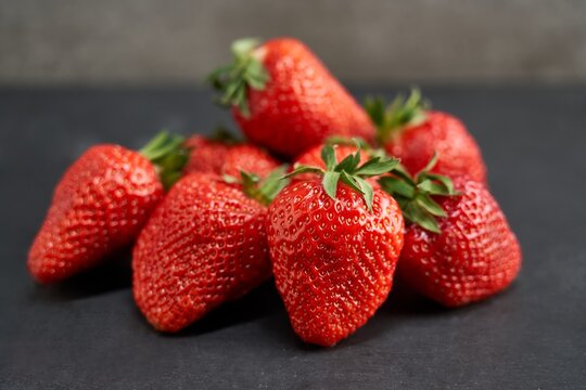 Close up image of fresh strawberries on black pale slab.