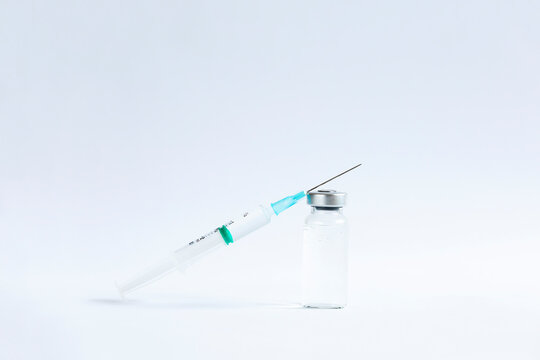 The vaccines vials glass bottle and disposable syringe on white