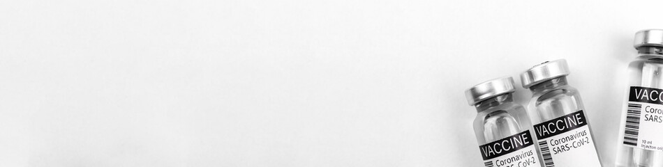 Coronavirus immunization banner with covid-19 vaccine vials on the white background, copy space and top view photo