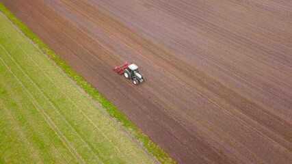 Fototapeta premium Traktor mit Gruber bewirtschaftet ein Acker, Landwirtschaft aus der Vogelperspektive 