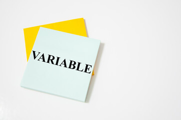 the variable text written on a white notepad with colored pencils and a yellow background