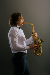 Studio portrait of young cool man with saxophone on dark background.