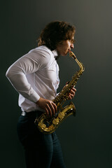 Studio portrait of young cool man with saxophone on dark background.