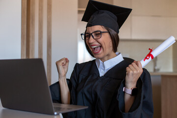 Happy smiling female student is graduating online at home with an online ceremony.  