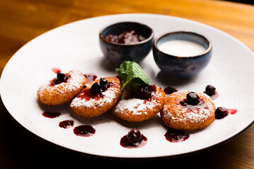 Beautifully decorated plate with some cheese pancakes, jam and cream.