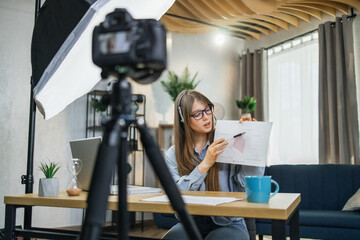 Attractive business woman in eyeglasses recording masterclass about success and finance. Pretty...