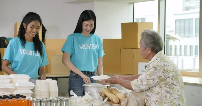 Group of Young asian male and female volunteers putting food on the plate and serving at homeless shelter as charity workers and members of community work to the poor during the Coronavirus pandemic. - Powered by Adobe