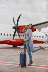 Obraz na płótnie Canvas Caucasian happy woman is smiling near plane before boarding