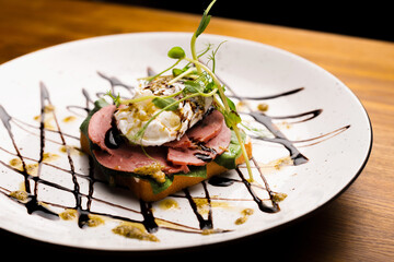 Close up photo of a plate with a ham sandwich beautifully decorated.