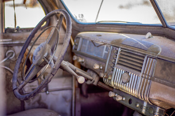 Interior view of the dash board of an old junked retro vehicle in a junkyard.