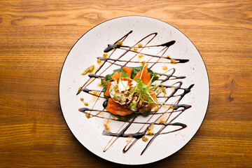 Top view photo of a plate with a salmon sandwich on a wooden table