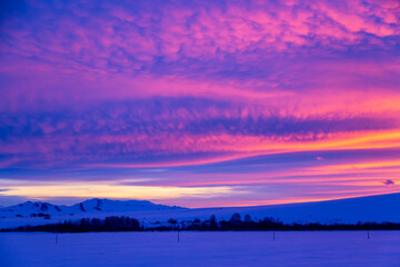 Fototapeta na wymiar Winter landscape with mountains during amazing vivid saturated beautiful sunset sky in pink, purple and blue colors. Sunset background.