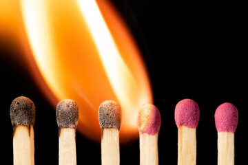 Close up shot of row of burning safety matches. Isolated fire on black background.