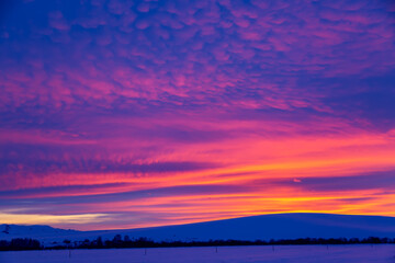 Fototapeta premium Winter landscape with mountains during amazing vivid saturated beautiful sunset sky in pink, purple and blue colors. Sunset background.