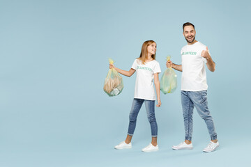 Full length two young friends couple teen girl man wears white t-shirt green volunteer hold bag trash walk isolated on pastel blue color background Voluntary free team work help charity grace concept