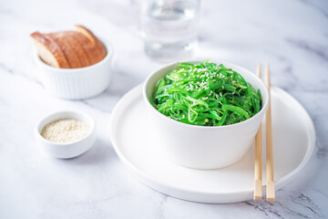 Green seaweed spicy salad with sesame seeds in a bowl