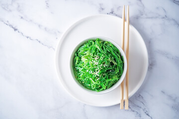 Green seaweed spicy salad with sesame seeds in a bowl