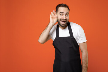 Young curious man barista bartender barman employee in black apron white t-shirt work in coffee...