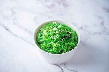 Green seaweed spicy salad with sesame seeds in a bowl