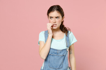 Young troubled puzzled thoughtful pensive caucasian woman in denim clothes blue t-shirt biting...