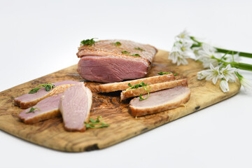 Smoked duck sliced with herbs on a wooden background.