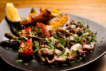 Photo of a plate with some shellfish prepared meat on wooden background.