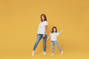 Fototapeta na wymiar Full body length happy woman in basic white t-shirt have fun child baby girl 5-6 years old hold hands dance Mom little kid daughter isolated on yellow color background studio Mother's Day love family
