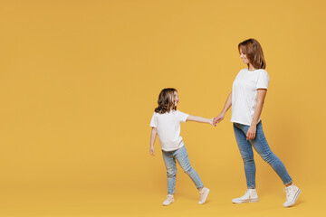 Full length happy woman in basic white t-shirt have fun child baby girl 5-6 years old hold hands...