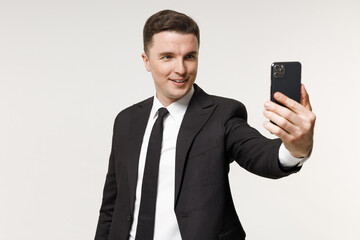 Young smiling successful employee business corporate lawyer man 20s wearing classic formal black grey suit shirt tie work in office do selfie shot on mobile phone isolated on white background studio.