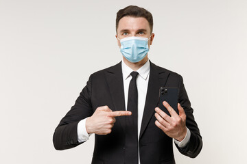 Young employee business corporate lawyer man 20s in classic black suit tie face mask coronavirus covid-19 pandemic quarantine work in office point on mobile cell phone isolated on white background