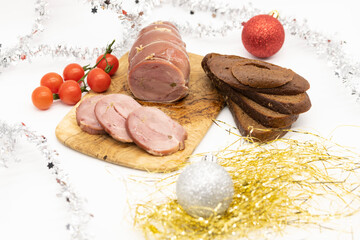 Baked Turkey roll with tomatoes and brown bread on a Christmas wooden background