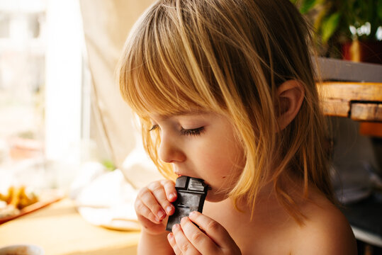little girl eating chocolate at home. Baby's diet, food, baby and sweets. High quality photo