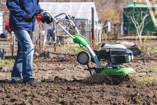 Farmer man plows the land with a cultivator preparing the soil for sowing