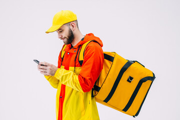 A young man of Caucasian appearance is waiting for an order, looks into the phone. Food delivery service concept.