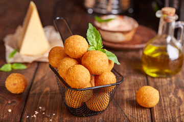 Deep fried Cheese balls. Delicious homemade appetizer. Freshly baked croquettes, served with basil leafs and sauce.