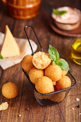 Deep fried Cheese balls. Delicious homemade appetizer. Freshly baked croquettes, served with basil leafs and sauce.