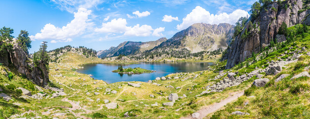 Fototapeta na wymiar Panoramic mountain lake surrounded by mountains with green grass on a lovely sunny summer day. Concept of mountain trip and summer vacations. Circo Saboredo, Aran Valley-Pyrenees, Catalonia, Spain.