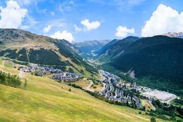 Aerial view of Baqueira Beret town in the Vall de Aran surrounded by beautiful green mountains on a sunny summer day. Summer tourism in Aran Valley, Pyrenees, Catalonia, Spain.