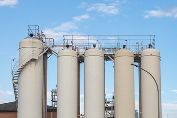 Big white vertical tanks against the sky. Large-scale chemical manufacturing