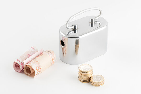 Metallic money box and Turkish Lira banknotes isolated on white background.