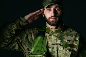 young marine corps soldier making a greeting gesture, against a dark background.