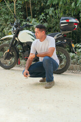 Naklejka premium Serious young ethnic biker in casual clothes near motorcycle