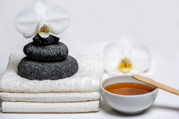 Fototapeta na wymiar spa style, white towels, honey cup, Zen stones, orchid: everything for a relaxing massage