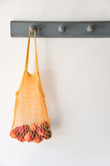 Reusable market bag with peaches hanging on an old coat rack