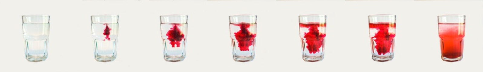 Stop motion image showing red dye poured into a glass of water